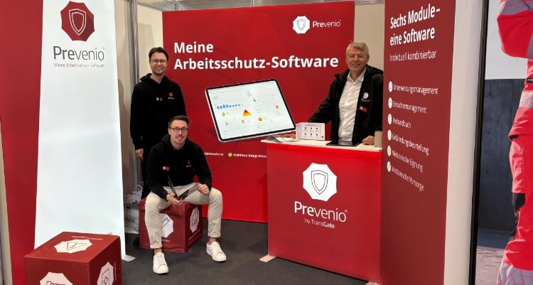 Messestand von Prevenio mit Präsentationsfläche zur Arbeitsschutz-Software, Informationscounter und Team vor einer großen Softwaredarstellung.