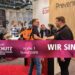 Messestand von Prevenio auf einer Fachmesse mit Besuchenden, Beratungsgesprächen und Präsentationsflächen.